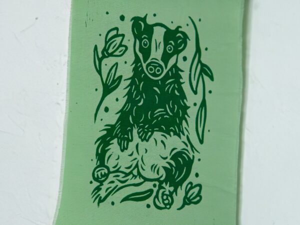 Grüner Stoffbanner mit aufgedrucktem Dachs, Blumen und Blättern (Detail)