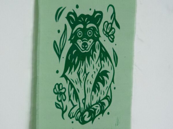 Grüner Stoffbanner mit aufgedrucktem Waschbären, Blumen und Blättern (Detail)