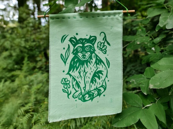 Grüner Stoffbanner mit aufgedrucktem Waschbären, Blumen und Blättern