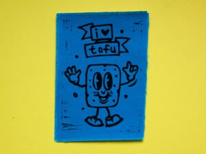 Blauer Aufnäher mit aufgedrucktem Comic-Tofu und dem Spruch "I Love Tofu" in Schwarz