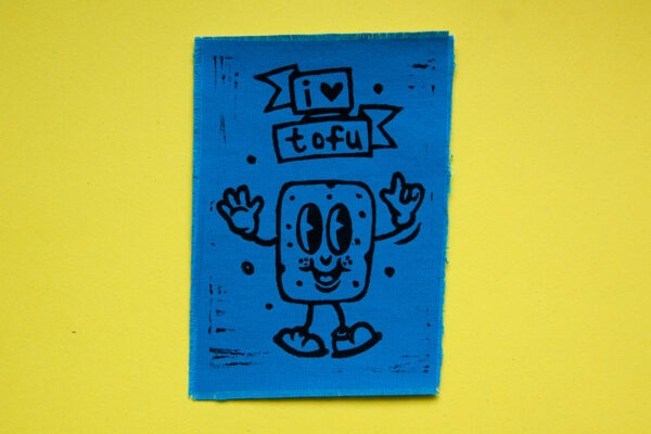 Blauer Aufnäher mit aufgedrucktem Comic-Tofu und dem Spruch "I Love Tofu" in Schwarz