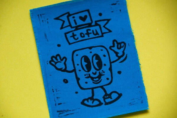 Blauer Aufnäher mit aufgedrucktem Comic-Tofu und dem Spruch "I Love Tofu" in Schwarz