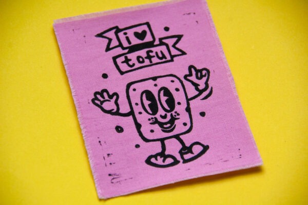 Rosa Aufnäher mit aufgedrucktem Comic-Tofu und dem Spruch "I Love Tofu" in Schwarz